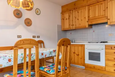 a kitchen with wooden cabinets and a table and chairs at Casa Maura in Soraga