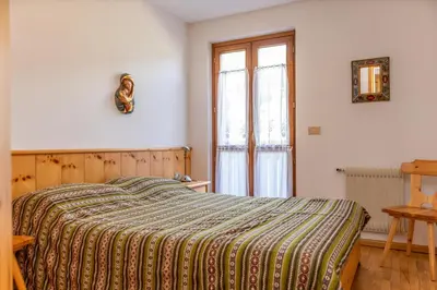 a bedroom with a bed with a striped blanket and a window at Casa Maura in Soraga