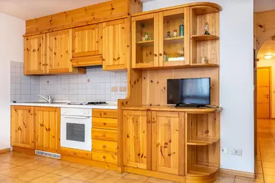 a kitchen with wooden cabinets and a tv at Casa Maura in Soraga