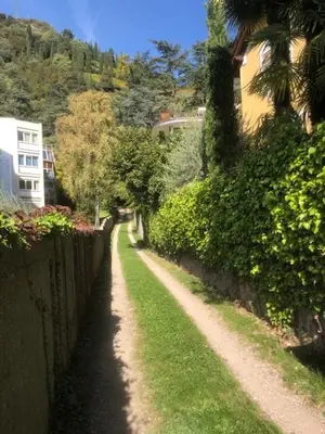 a dirt road next to a fence and a house at TORRE GARDEN HOME - casa singola nella città di Bolzano con giardino privato in Bolzano
