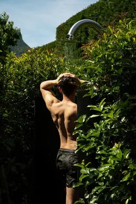 a shirtless man standing next to a water fountain at Hotel Magdalener Hof in Bolzano