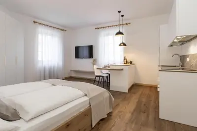 a white bedroom with a bed and a desk at Ansitz von Wohlgemuth in Salorno sulla Strada del Vino