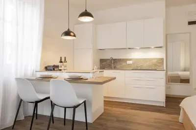 a kitchen with white cabinets and a island with white chairs at Ansitz von Wohlgemuth in Salorno sulla Strada del Vino