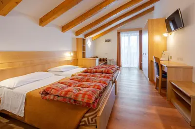 a hotel room with three beds and a television at Hotel Cristallo in Vigo di Fassa