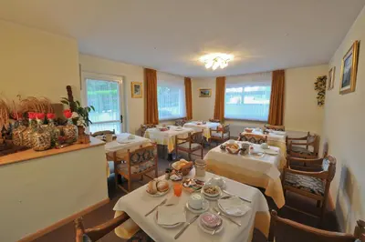 a restaurant with tables and chairs with white tablecloths at Hotel Cristallo in Vigo di Fassa