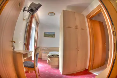 a small room with a desk and a bedroom at Hotel Cristallo in Vigo di Fassa