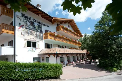 a building with people sitting outside of it at Hotel Cristallo in Vigo di Fassa