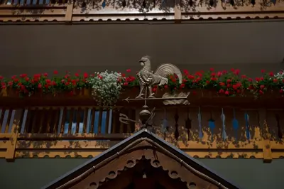 a statue of a rooster on a balcony with flowers at Hotel Cristallo in Vigo di Fassa