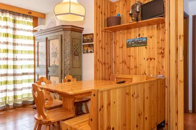 a dining room with a wooden table and chairs at Residence Marmolada in Pozza di Fassa