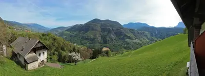 a view of a green hill with a house on it at Pirchnerhof in Longomoso