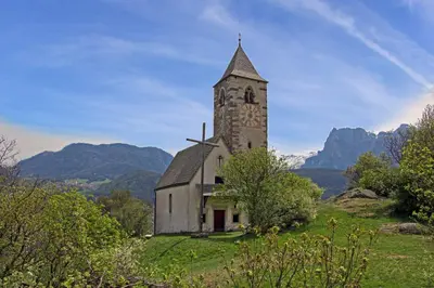 an old church on a hill with mountains in the background at Pirchnerhof in Longomoso