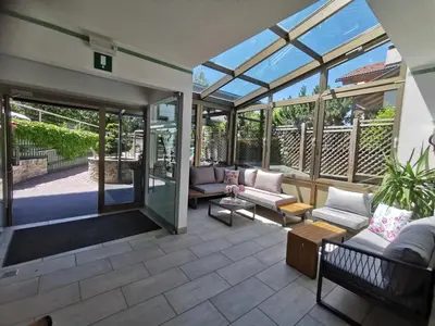 a conservatory with glass doors and a patio at Hotel Akelei in Brunico
