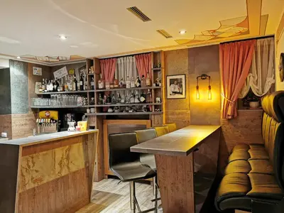 a bar with a counter and chairs in a room at Hotel Akelei in Brunico