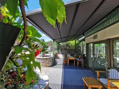 an outdoor patio with awning and tables and chairs at Hotel Akelei in Brunico