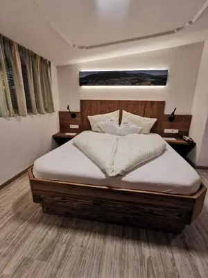 a bedroom with a large bed with white sheets at Hotel Akelei in Brunico