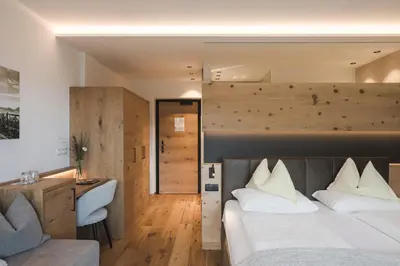 a bedroom with a bed and a desk and a chair at Naturhotel Gruberhof in Schenna