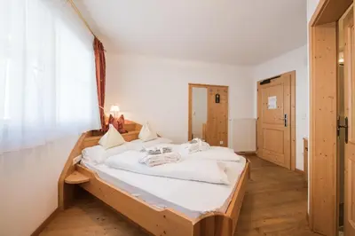 a bedroom with a large bed with white sheets at Naturhotel Gruberhof in Schenna