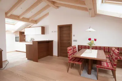 a kitchen and dining room with a wooden table and chairs at Apartmenthaus Gruberhof in Schenna