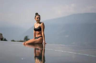 a woman in a bikini sitting on the water at Apartmenthaus Gruberhof in Schenna