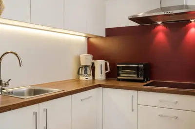 a kitchen with white cabinets and a sink and a microwave at Apartmenthaus Gruberhof in Schenna