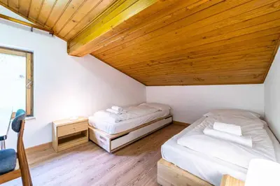 two beds in a room with a wooden ceiling at Casa Mirabella in Sottoguda