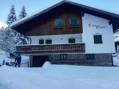 a man standing in the snow in front of a building at Cesa Elena in Canazei