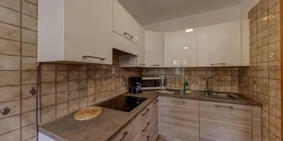a kitchen with white cabinets and a sink at Cesa Elena in Canazei
