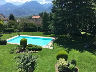a pool in a yard with mountains in the background at sonnige schicke Ferienwohnung Meran Pienzenau in Merano