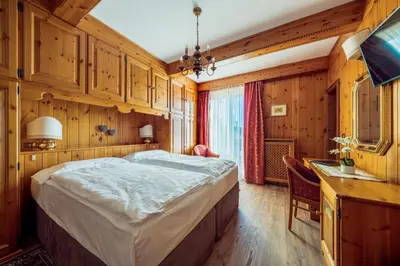 a bedroom with a large bed and a desk with a desk at Hotel Columbia & Spa in Cortina dʼAmpezzo