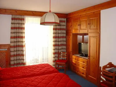 a bedroom with a red bed and a television at Hotel Columbia & Spa in Cortina dʼAmpezzo