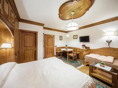 a bedroom with a bed and a couch and a table at Hotel Columbia & Spa in Cortina dʼAmpezzo