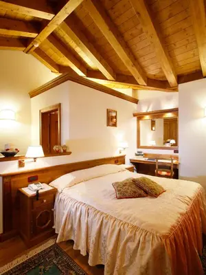 a bedroom with a large bed and wooden ceilings at Hotel Columbia & Spa in Cortina dʼAmpezzo