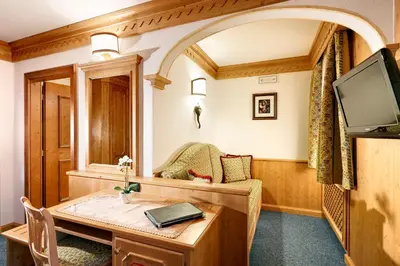 a living room with a table and a tv at Hotel Columbia & Spa in Cortina dʼAmpezzo