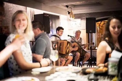 a group of people sitting around a table playing instruments at Hotel Platz in Ortisei