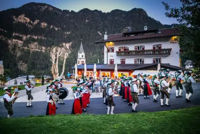 a large group of people in costumes walking in front of a building at Hotel Platz in Ortisei