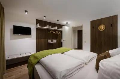 a bedroom with a large bed with a tv on the wall at Sambock Quarter Pustrabase in Brunico