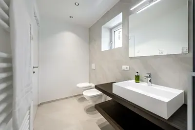 a white bathroom with a sink and a toilet at Sambock Quarter Pustrabase in Brunico