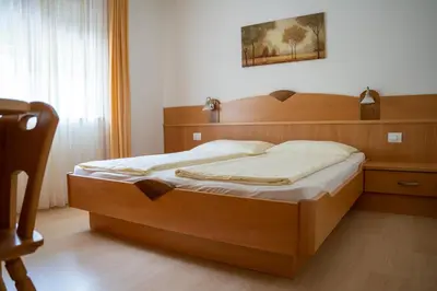 a bed in a bedroom with a wooden headboard at Tribus Lorenz - Wiesgut in Vollan