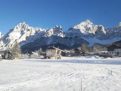 a snow covered village with snowy mountains in the background at Casa Antelao in San Vito di Cadore