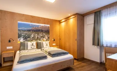 a bedroom with a bed with a picture on the wall at Apartments Picenin in La Villa