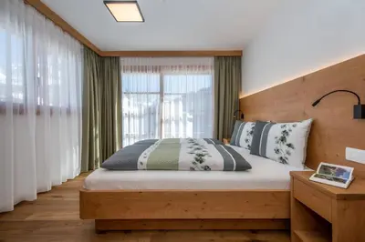 a bedroom with a bed and a large window at Apartments Picenin in La Villa