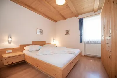 a bedroom with a large bed in a room with a window at Mareithof Appartements Seeblick in Caldaro