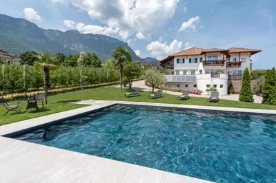 a large swimming pool in front of a house at Mareithof Appartements Seeblick in Caldaro
