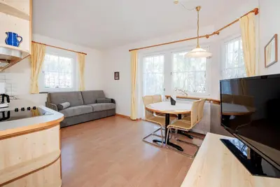 a kitchen and living room with a table and a couch at Mareithof Appartements Seeblick in Caldaro