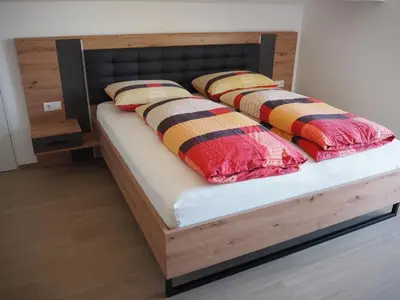 a bed with a wooden frame and two pillows on it at Ebner Appartements in Aldino