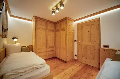 a bedroom with two beds and a wooden door at Apartments Berna in Ortisei