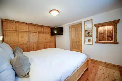 a bedroom with a white bed and wooden cabinets at Apartments Berna in Ortisei