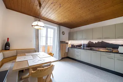 a kitchen with a table and a couch and a window at Apartments Stua da Carlo in Ortisei