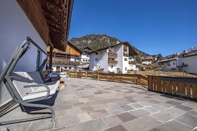 a chair on the balcony of a house at Apartments Praruf in Selva di Val Gardena