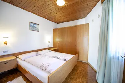 a bedroom with a large bed with a wooden headboard at Apartments Praruf in Selva di Val Gardena